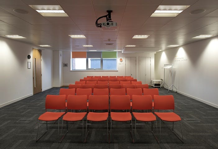 Aspire meeting space in Glasgow with orange chairs, perfect for workshops and presentations.