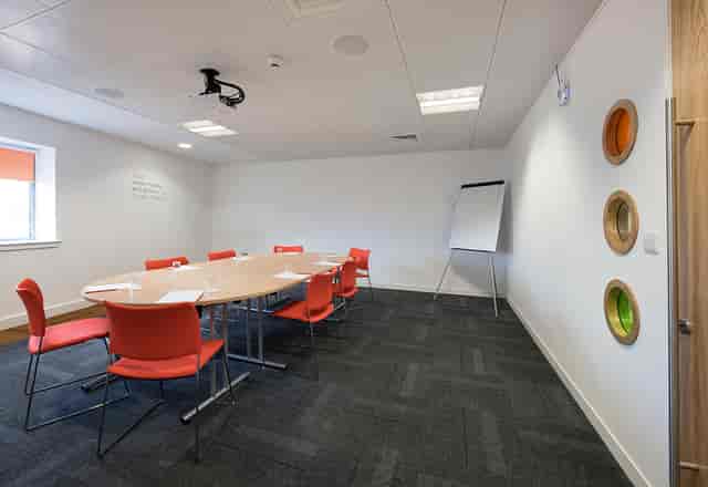 Modern meeting room at Twist in Glasgow with round table and orange chairs for collaboration.