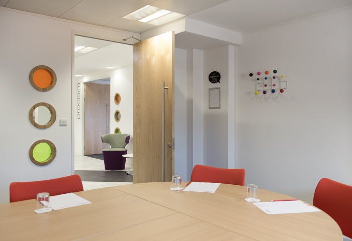 Modern meeting room at Twist in Glasgow with round table and red chairs for collaboration.