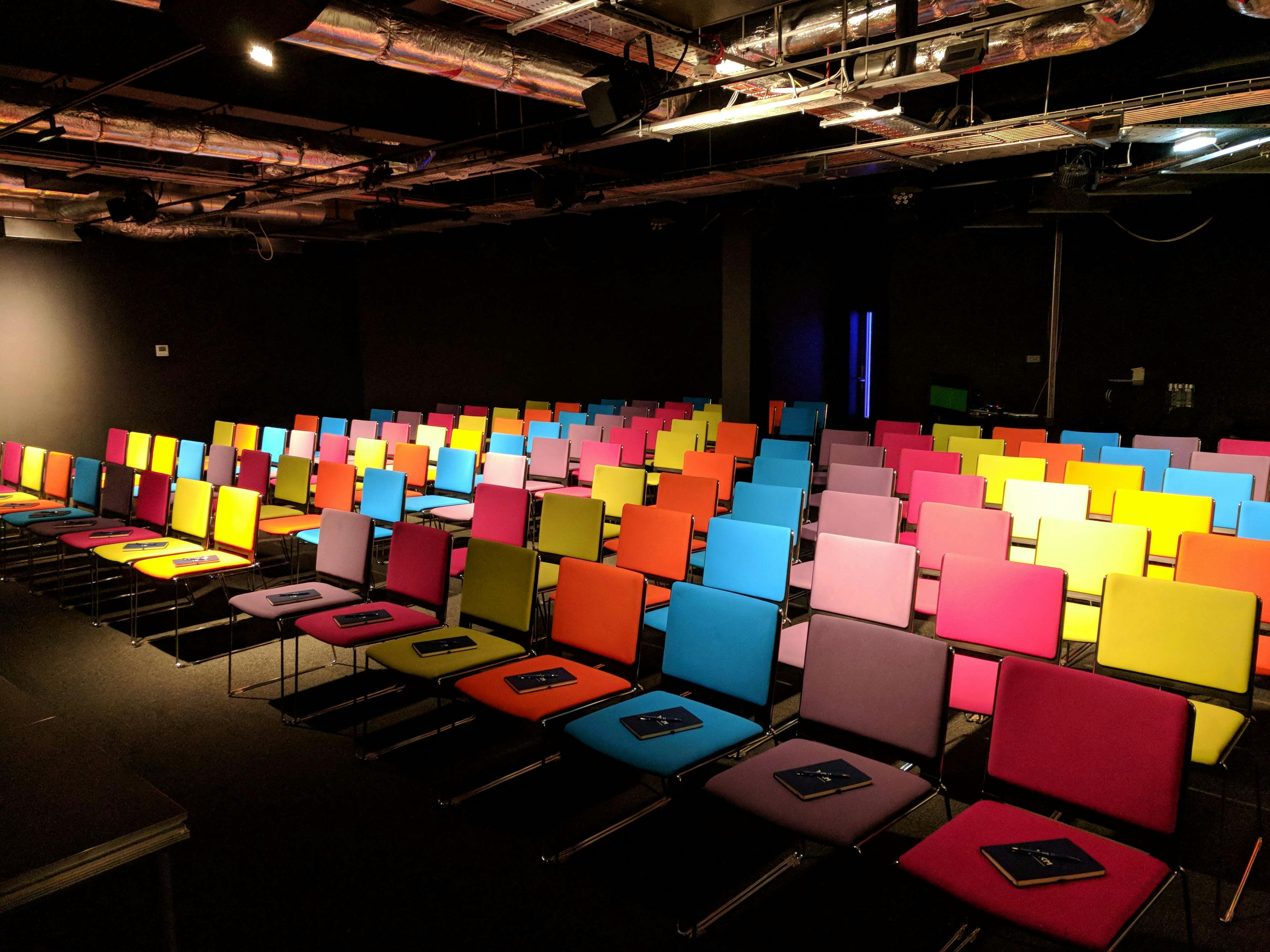 Modern auditorium with colorful chairs, perfect for workshops and presentations.