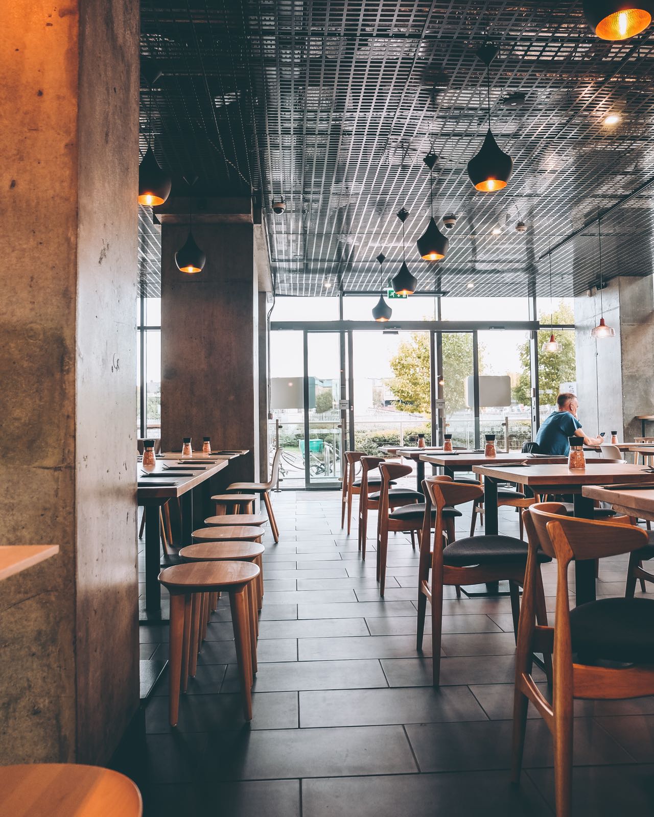 Modern restaurant venue with large windows, perfect for casual meetings and small events. - Banner