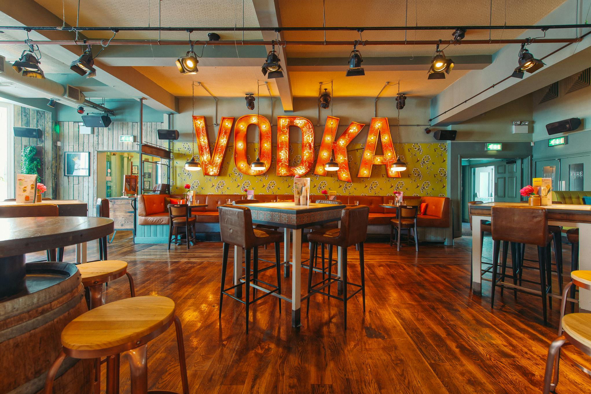 Vibrant event space with bold "VODKA" sign for casual gatherings in Revolution Brighton.