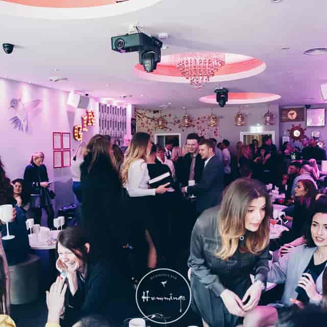 Vibrant networking event at stylish venue with engaged attendees enjoying drinks.