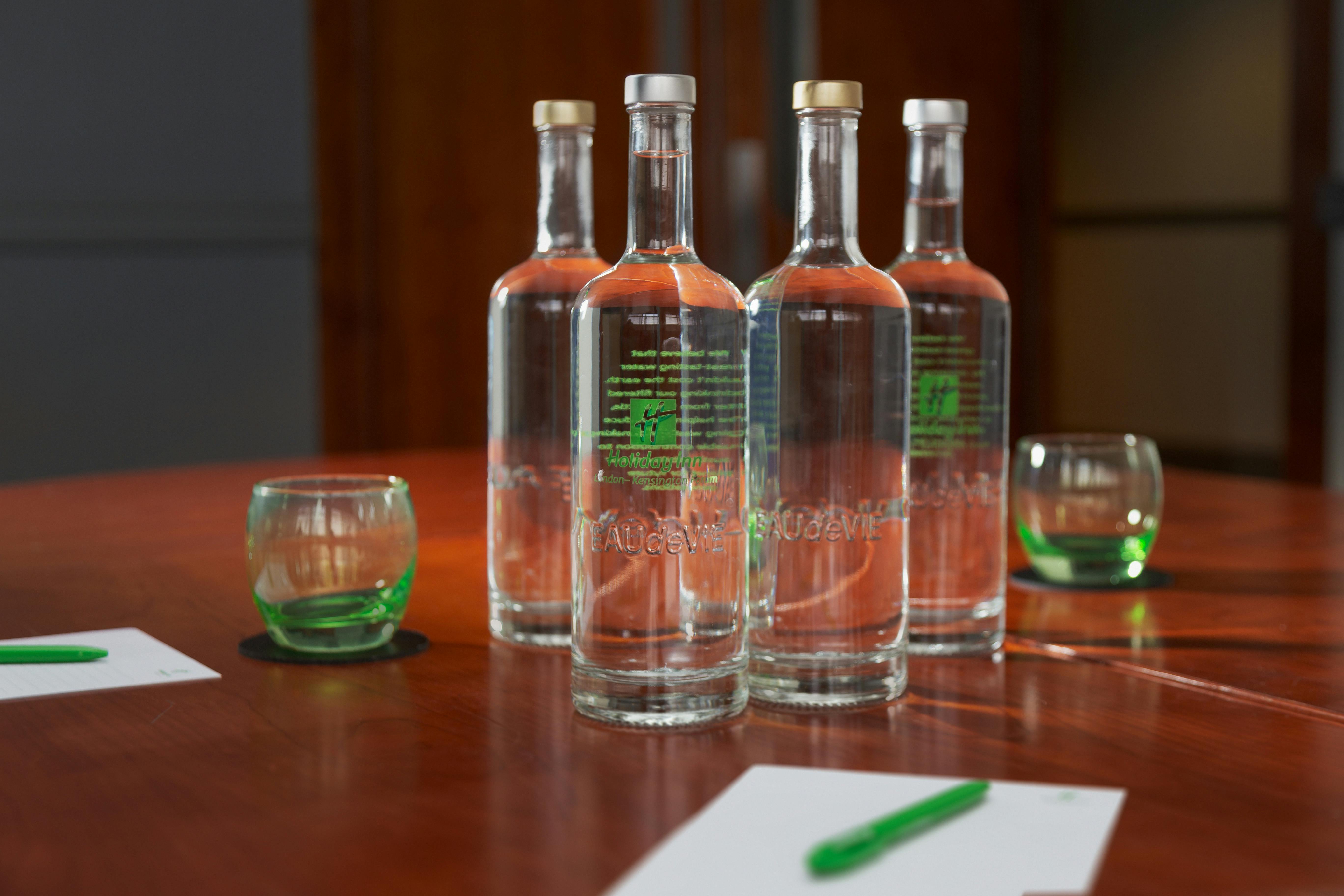 Polished meeting setup with glass bottles and green glasses at Holiday Inn Kensington.