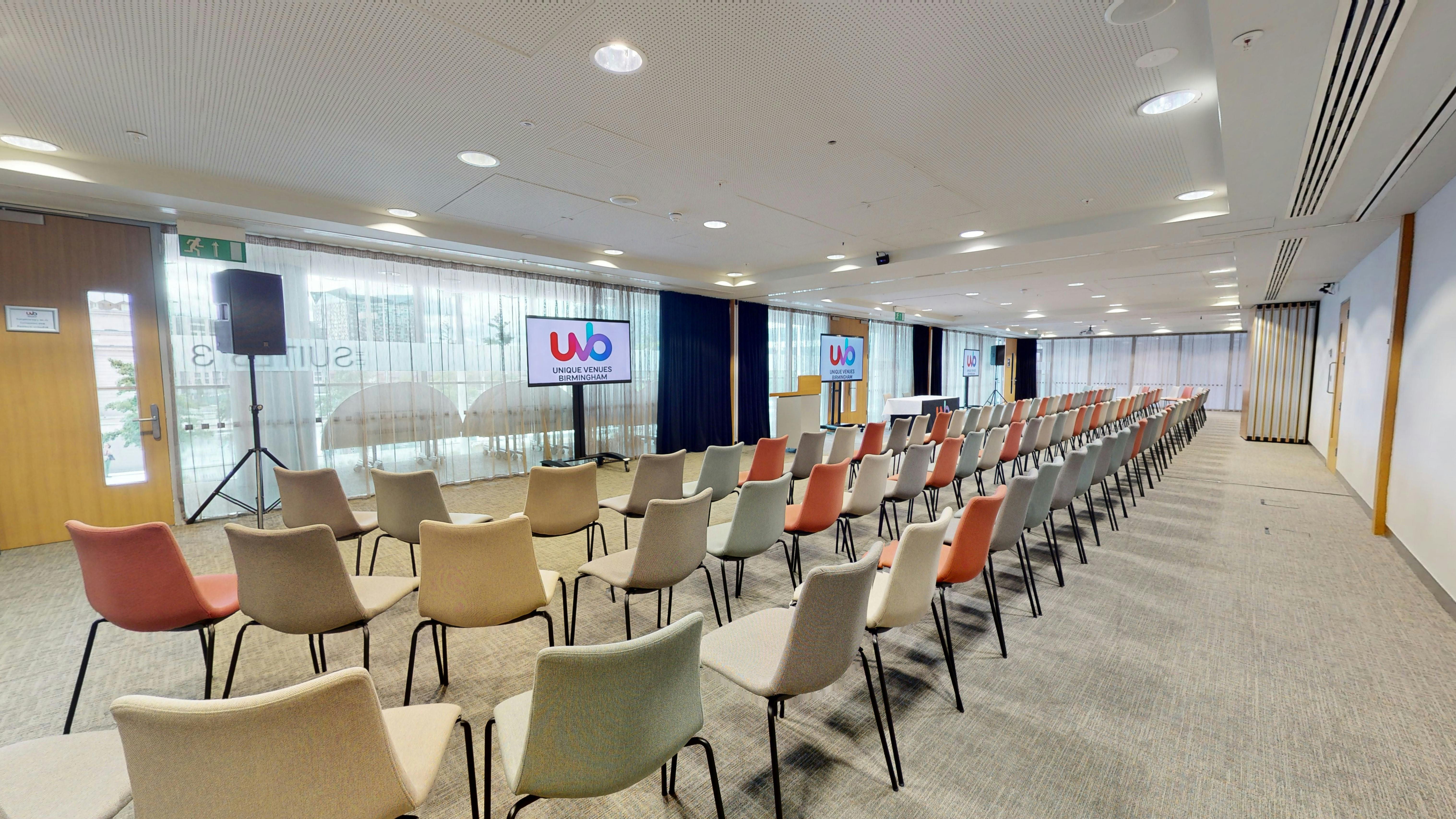 Event space with colorful chairs and dual screens for presentations in Birmingham.
