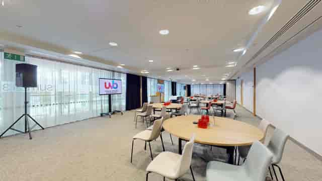 Versatile meeting room with round tables and large screen for corporate events in Birmingham.