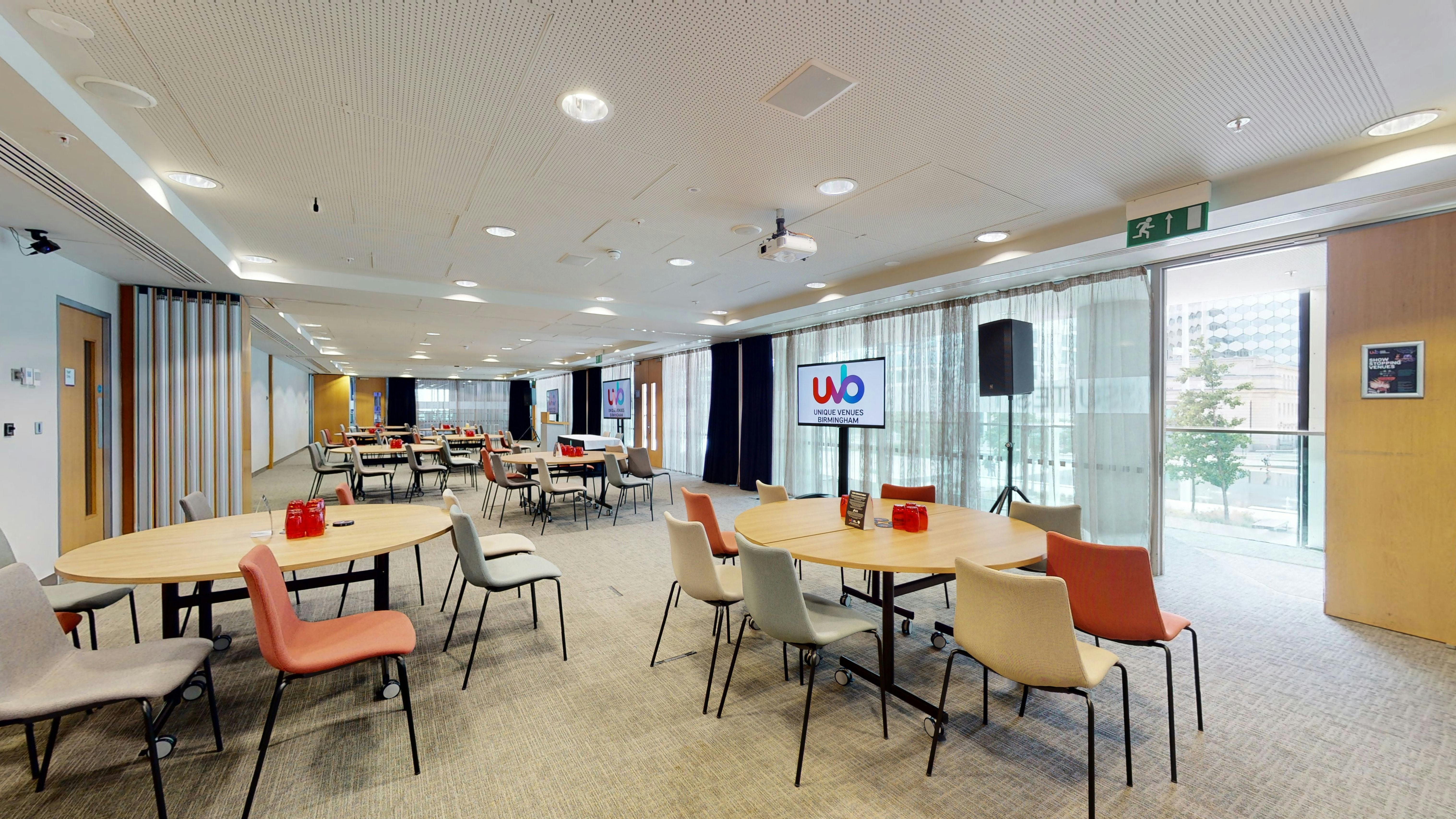 Versatile meeting room with round tables, ideal for workshops and networking events.