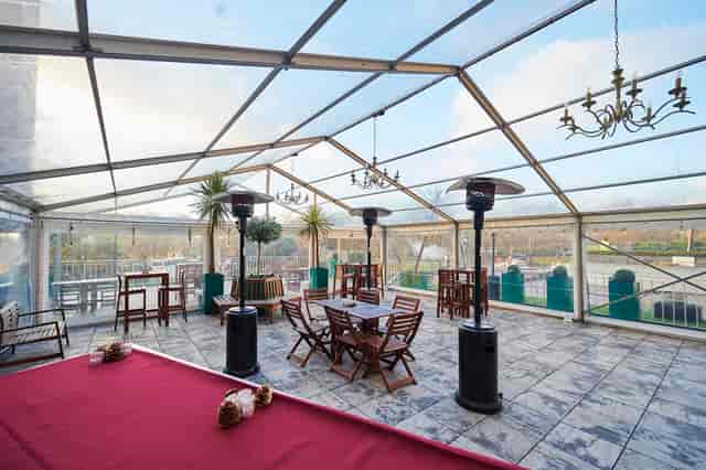 Elegant clear tent wedding venue with chandeliers, ideal for receptions and corporate events.