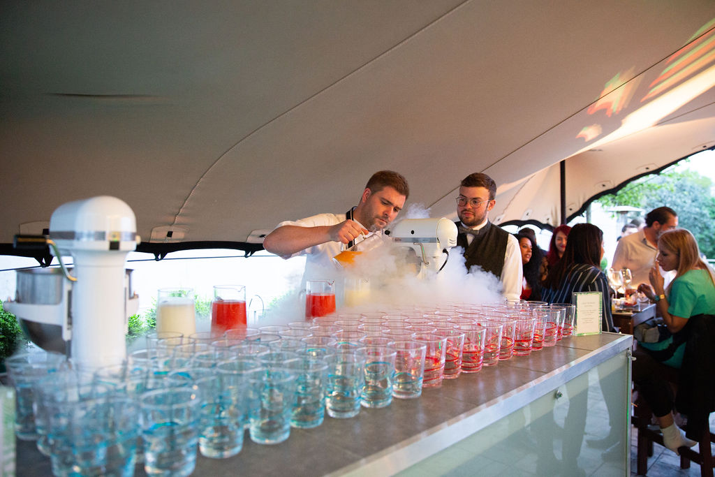 Outdoor summer party beverage station with colorful cocktails and dry ice effects. - Banner