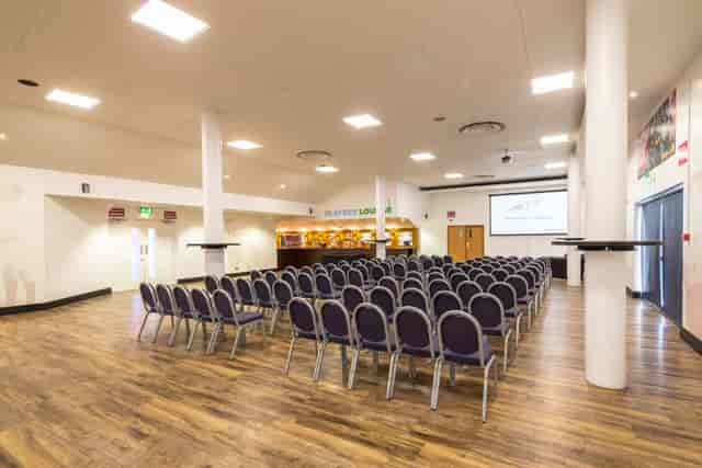 Players in Twickenham Stoop Stadium set for a conference presentation with chairs arranged.