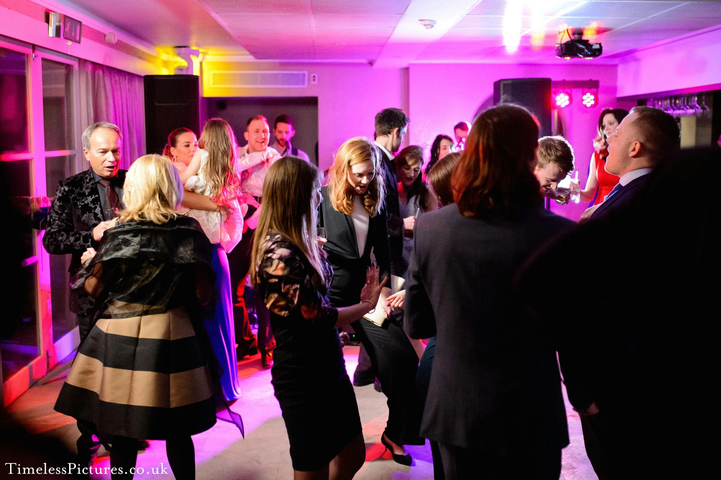 Vibrant gala in The Bingham's Garden Room 3 with attendees dancing under colorful lights.