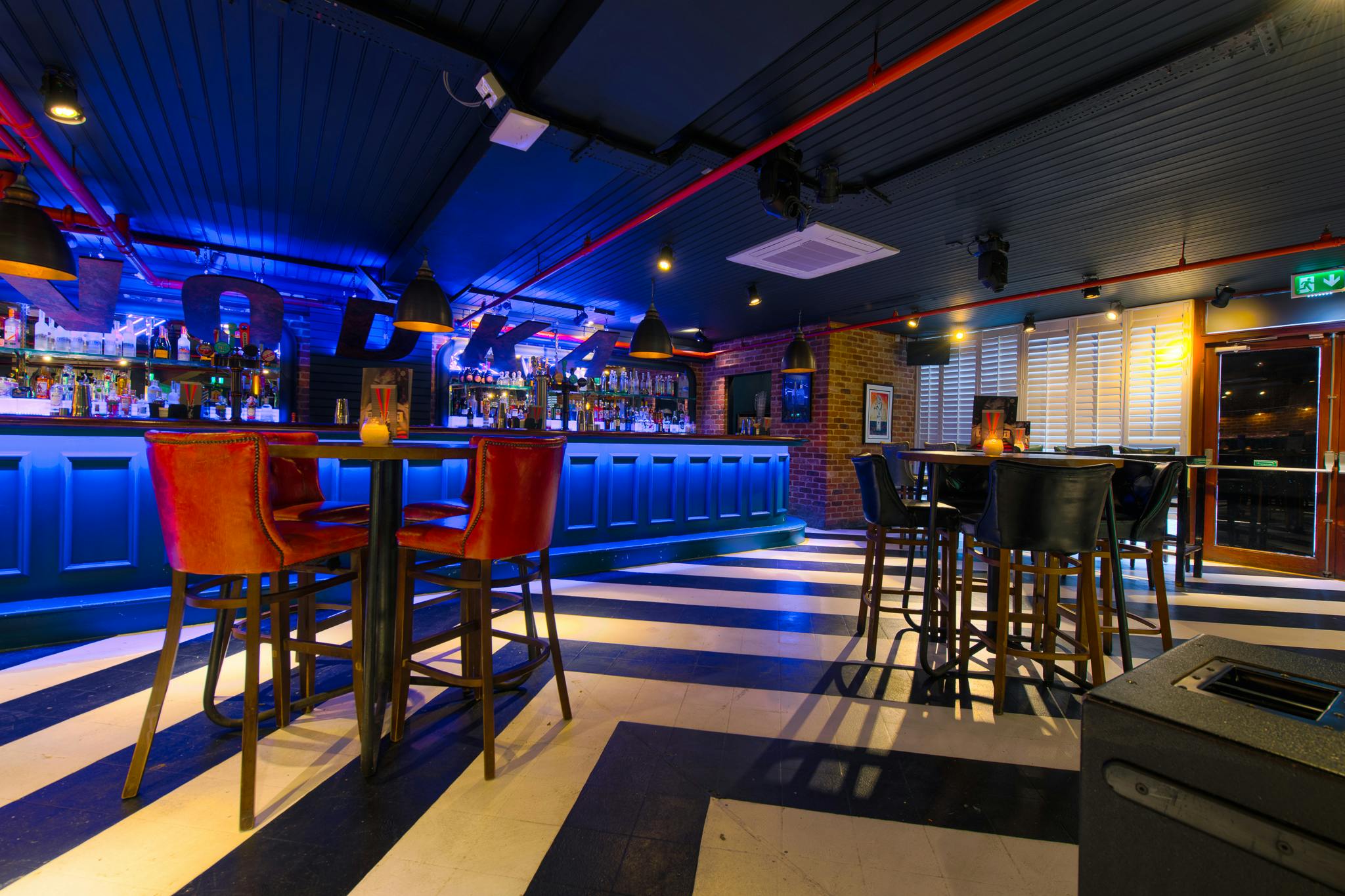 Stylish event space with modern bar and blue lighting for networking or social gatherings.