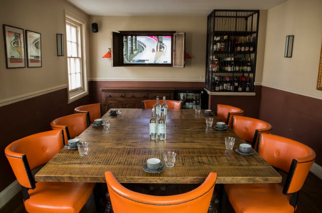 Private dining room with wooden table and orange chairs, perfect for meetings or events.