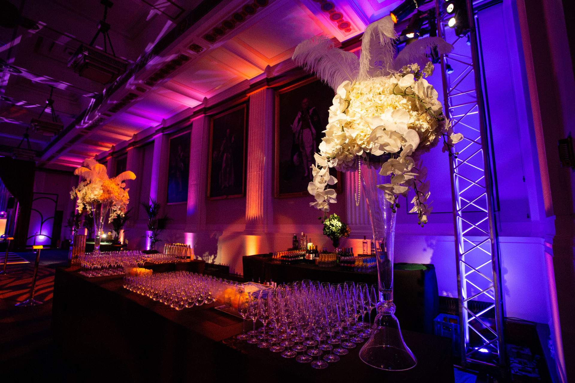 Elegant Christmas party setup with floral arrangements and purple lighting at Freemasons' Hall. - Banner