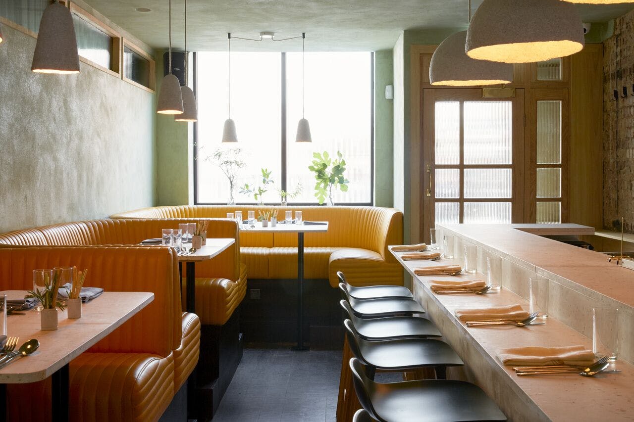 Stylish restaurant interior with cozy yellow banquettes, ideal for networking events.