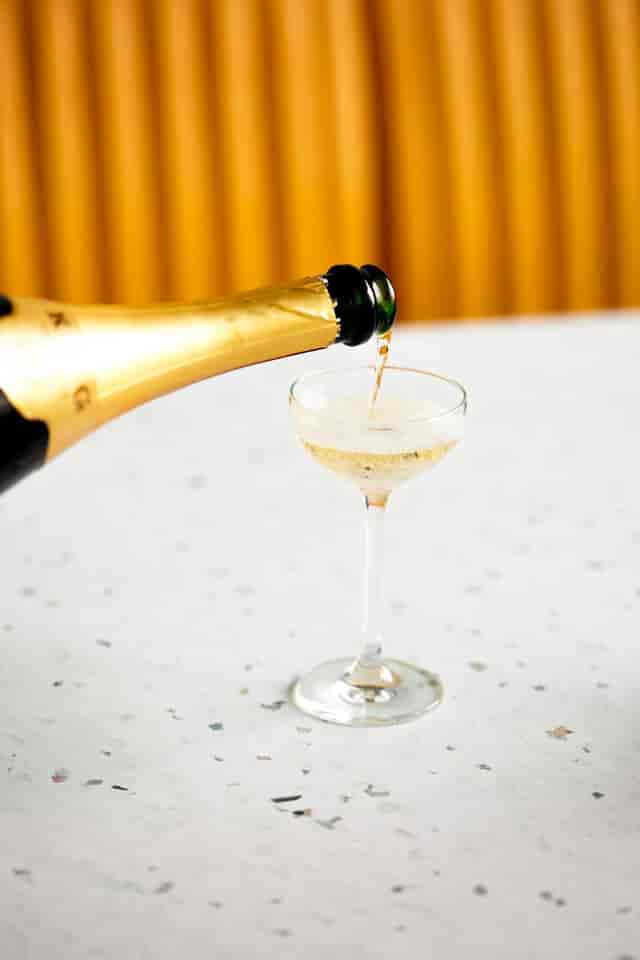 Champagne being poured into a coupe glass for elegant wedding celebrations.