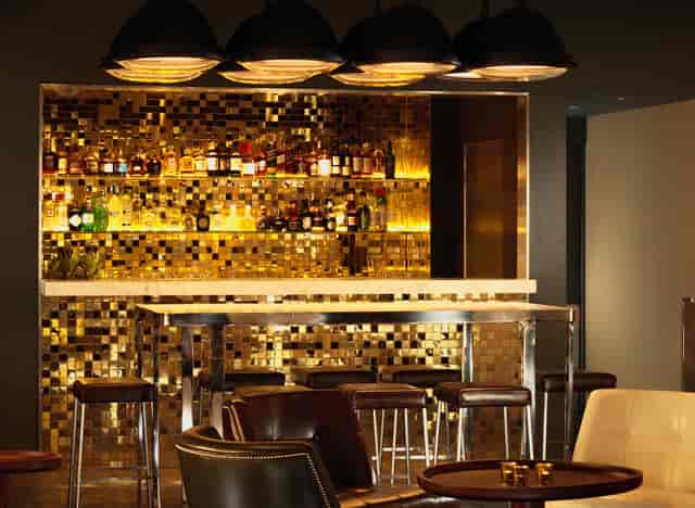 Sleek bar with gold mosaic backdrop, perfect for upscale cocktail receptions and events.