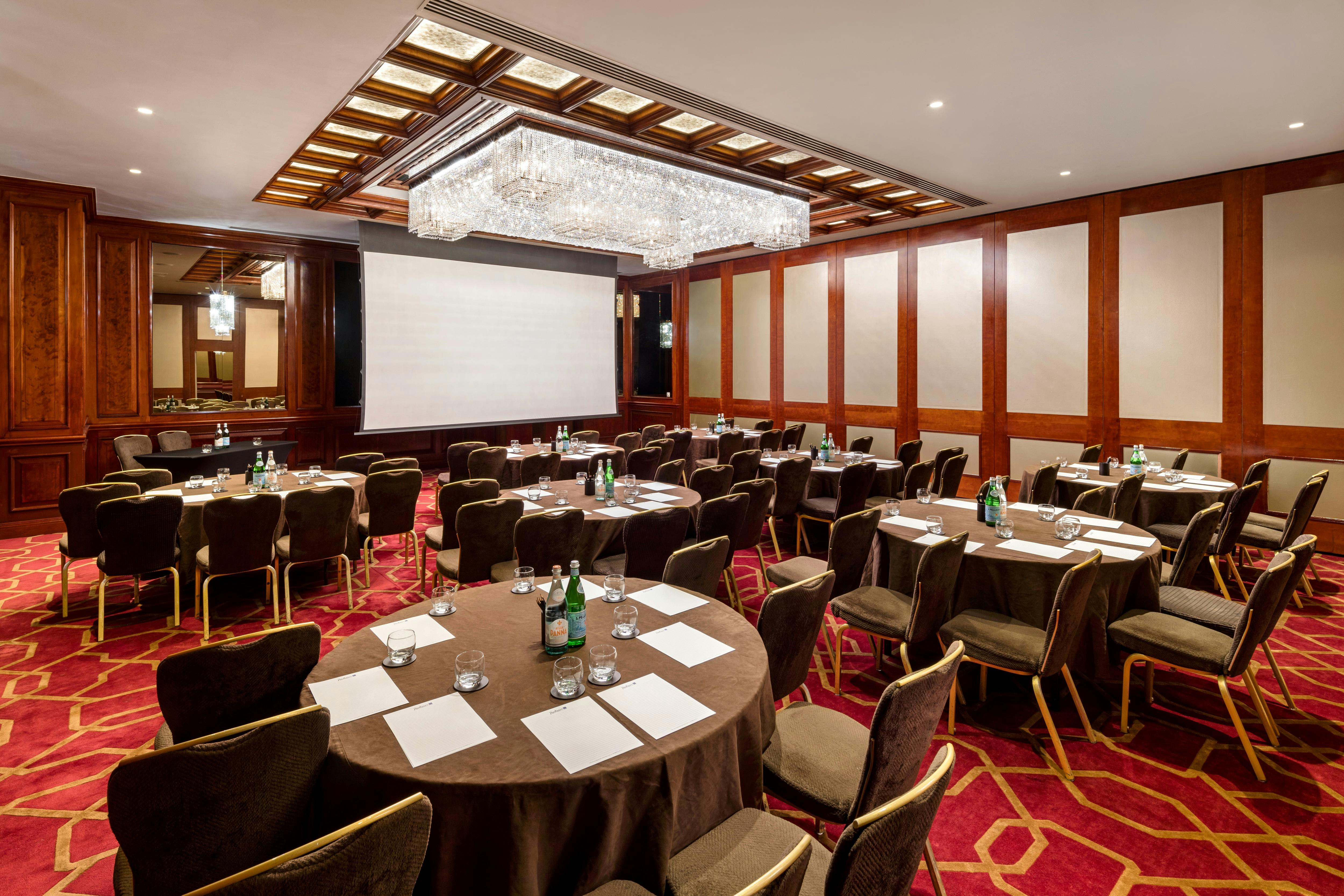 Corporate meeting room with round tables and elegant chandelier at Radisson Blu Heathrow.