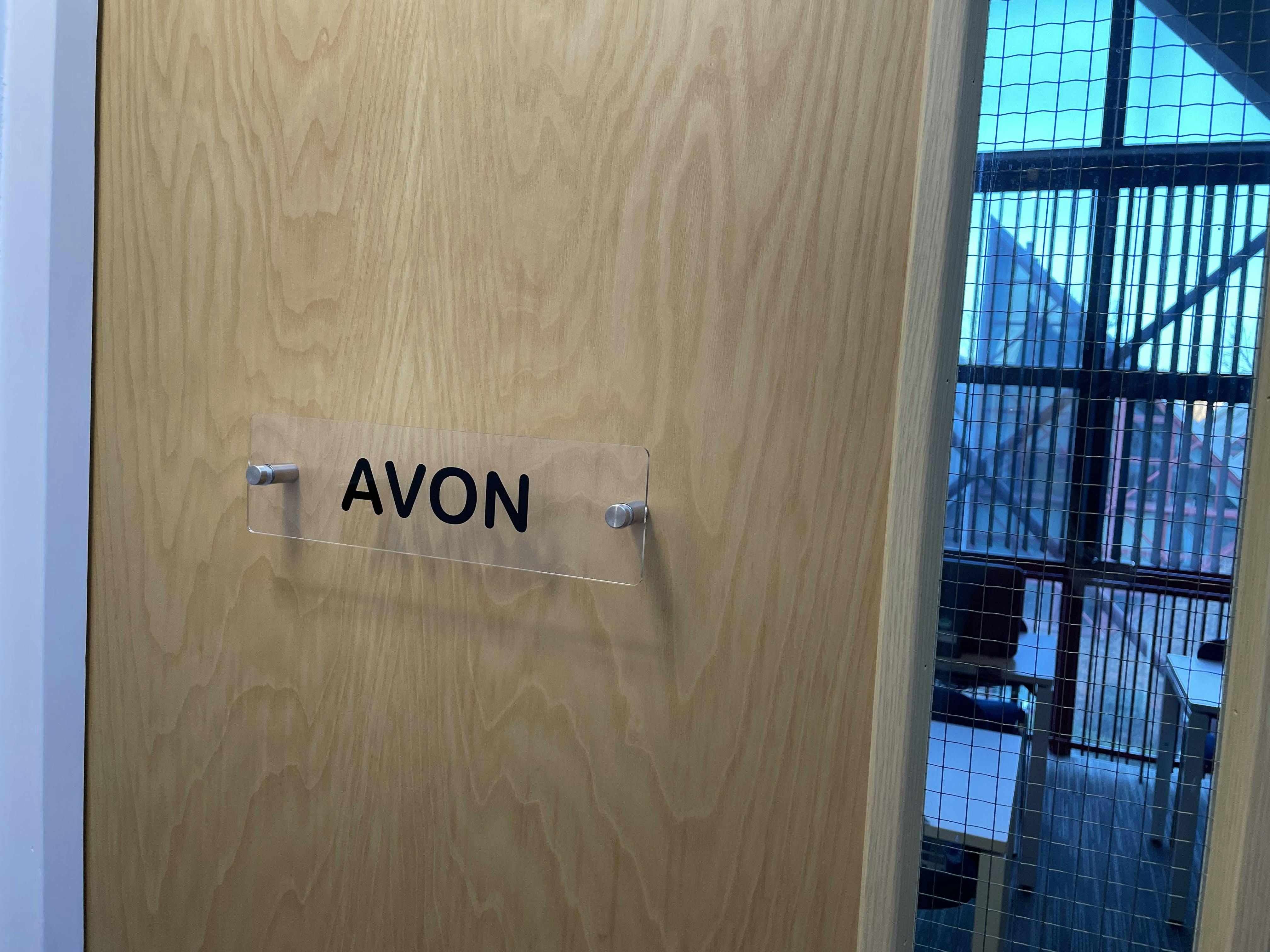 Modern door with "AVON" sign in Suite Avon, ideal for corporate meetings and workshops.