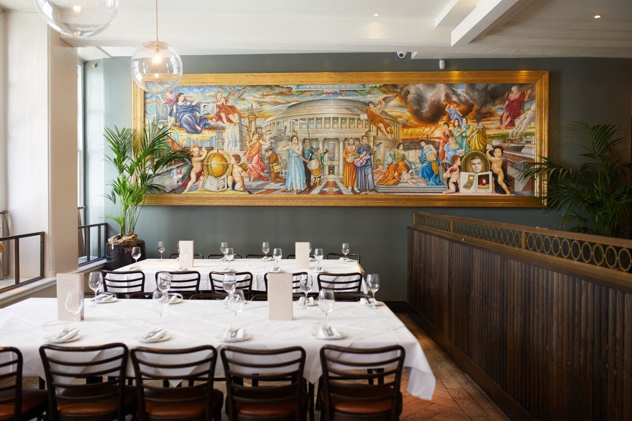 Elegant dining space for events at Gusto Restaurant, Manchester with striking mural backdrop.