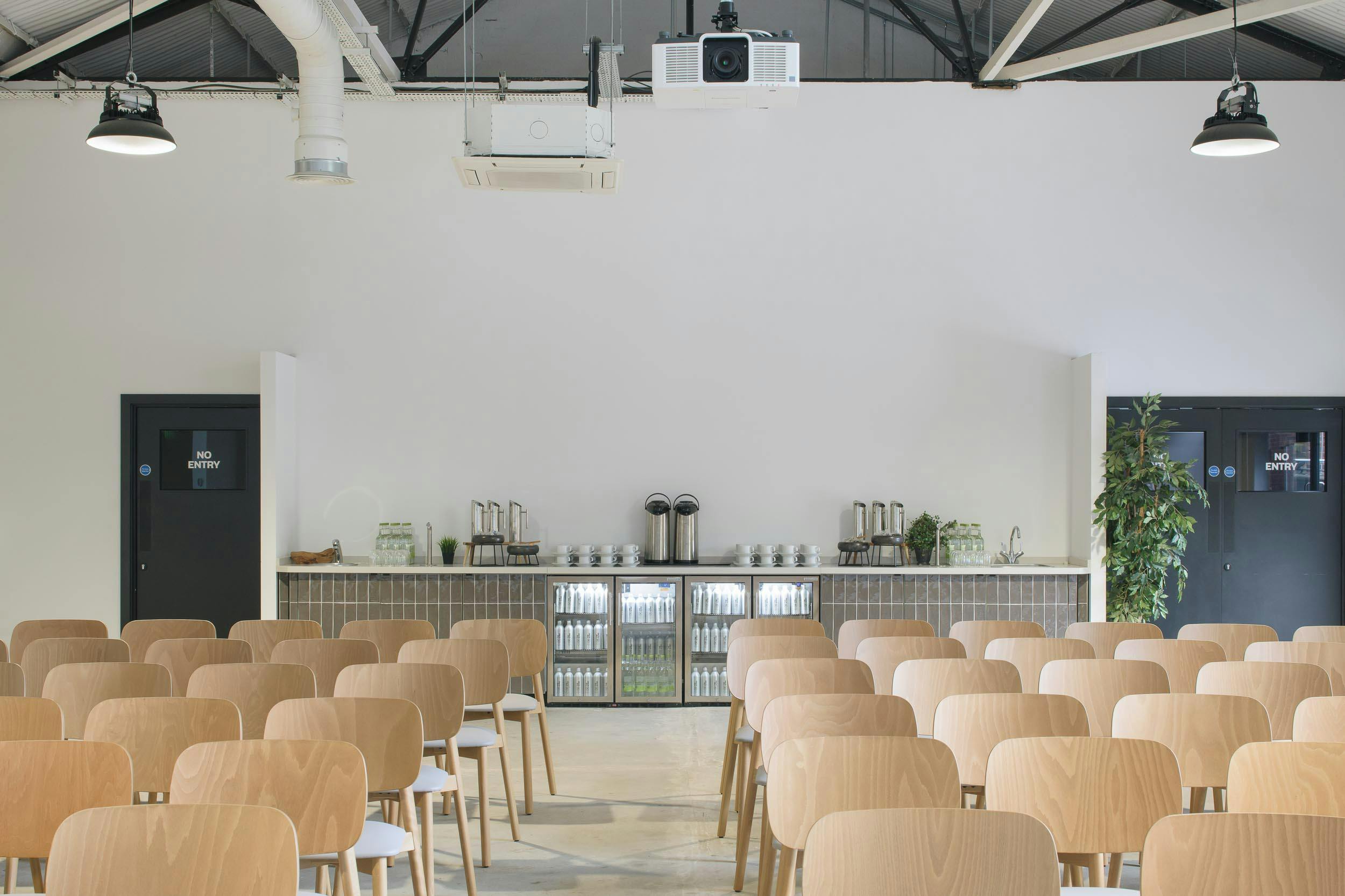 Gatehouse meeting space with wooden chairs, projector, ideal for events and collaboration.