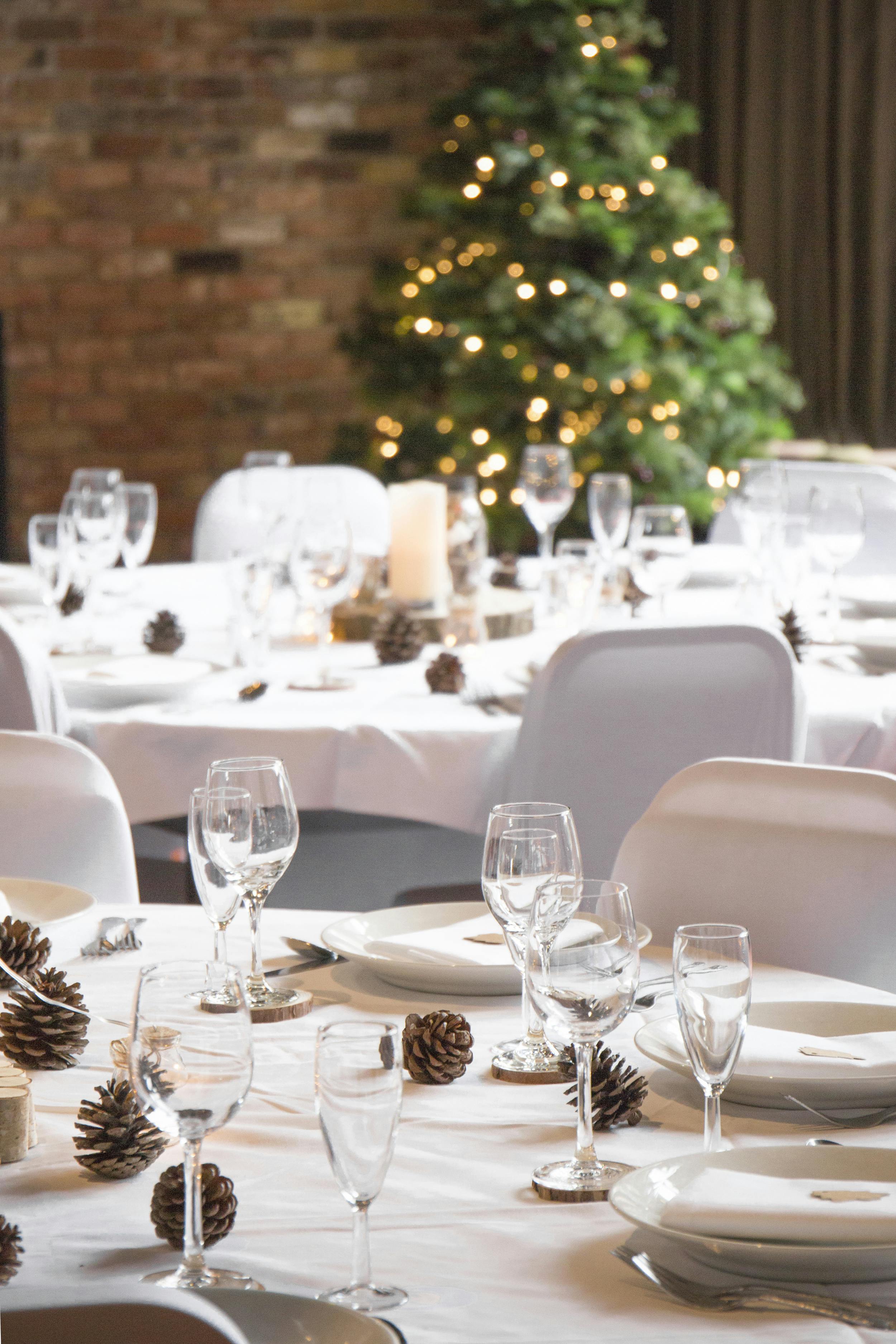 Elegant dining setup in Dickens Inn for festive events with warm ambiance and pinecone centerpieces.