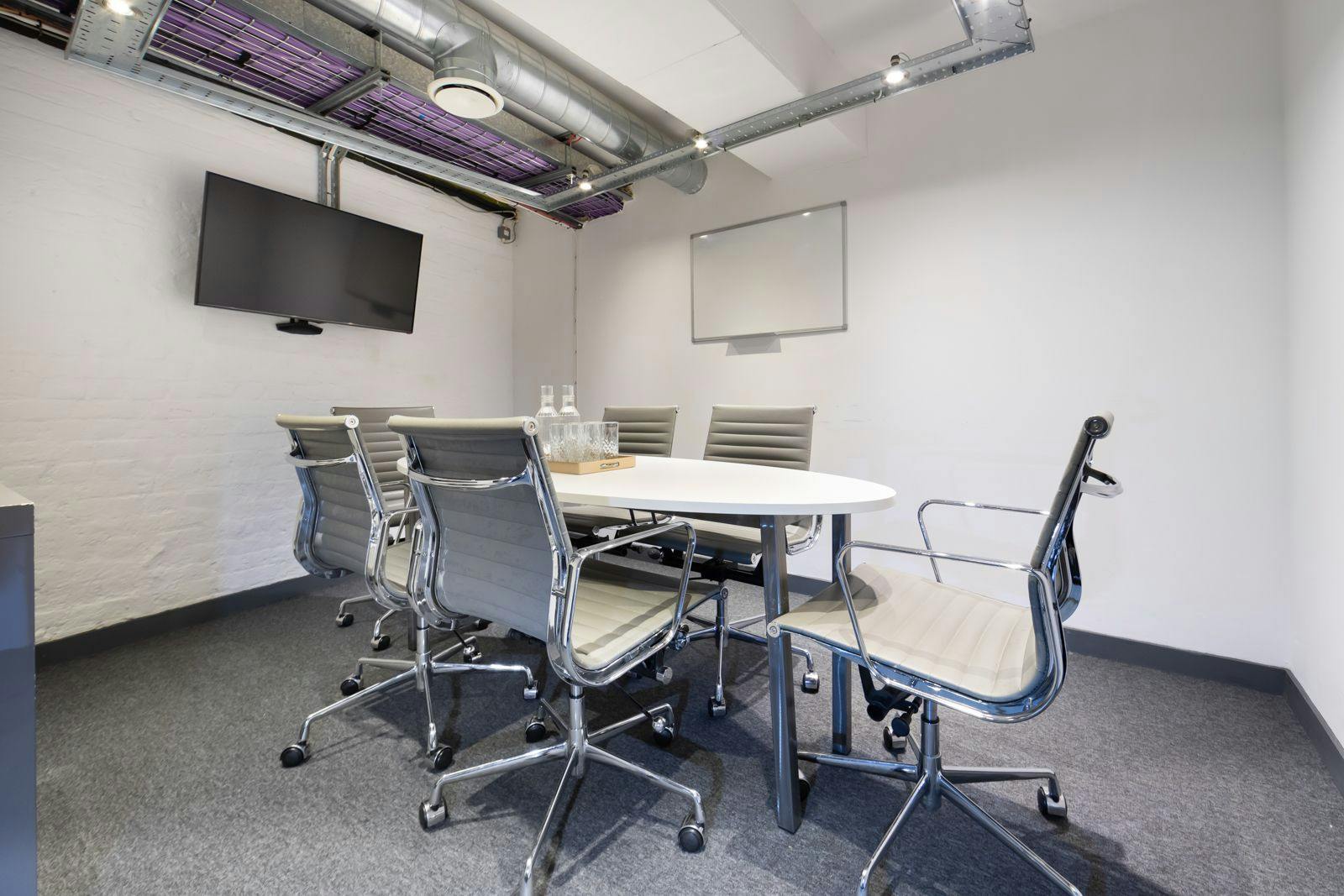 Modern meeting room with round table and dual screens for collaborative events.