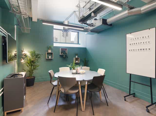 Modern meeting room with teal walls for collaborative brainstorming sessions.