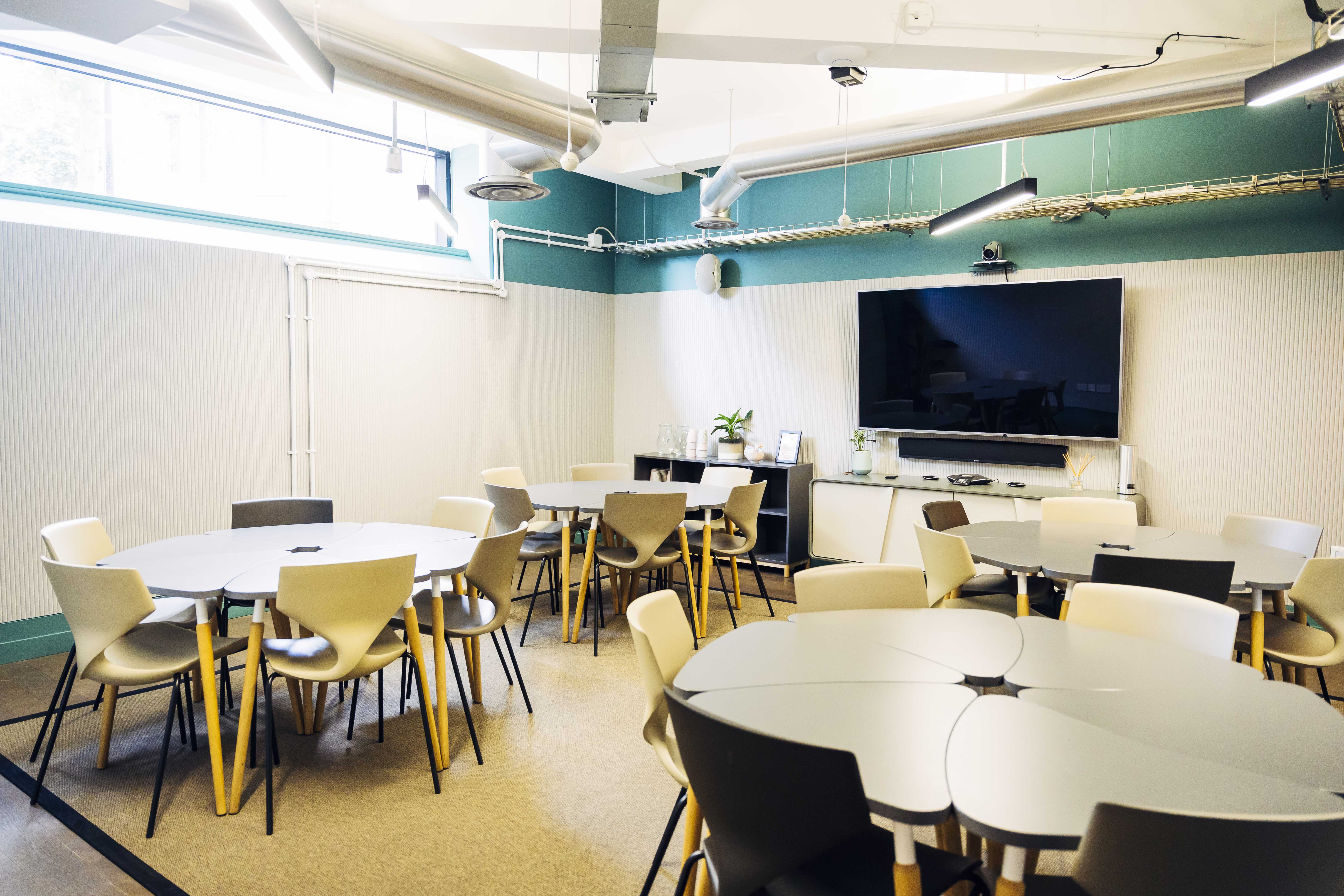 Versatile meeting room with round tables for workshops in Uncommon Borough.