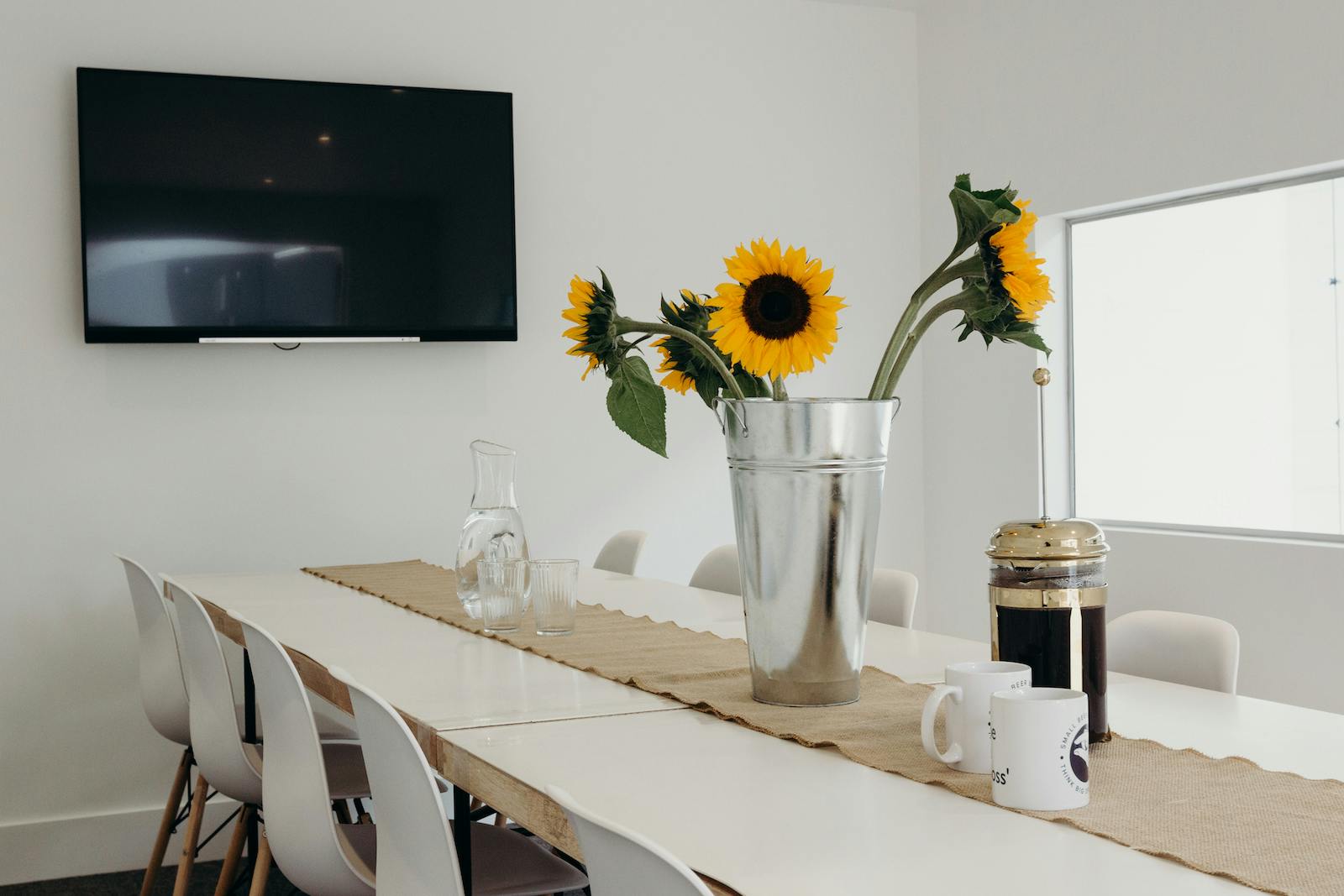 Modern boardroom with long table, sunflowers; perfect for meetings and brainstorming.