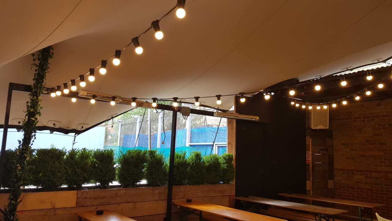 Outdoor event space at Bermondsey Bar & Kitchen with string lights and communal tables.