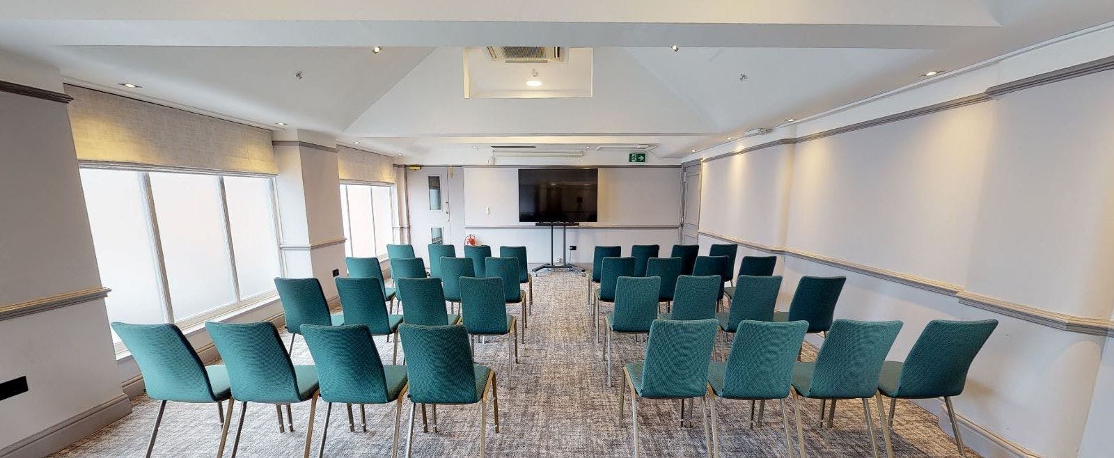 Well-lit meeting room with teal chairs for presentations at Delta Hotels Manchester Airport.