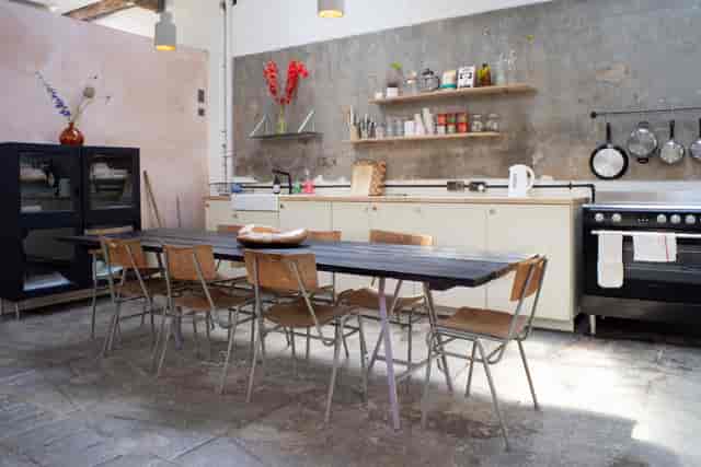 Modern kitchen space with long table for culinary events and gatherings.