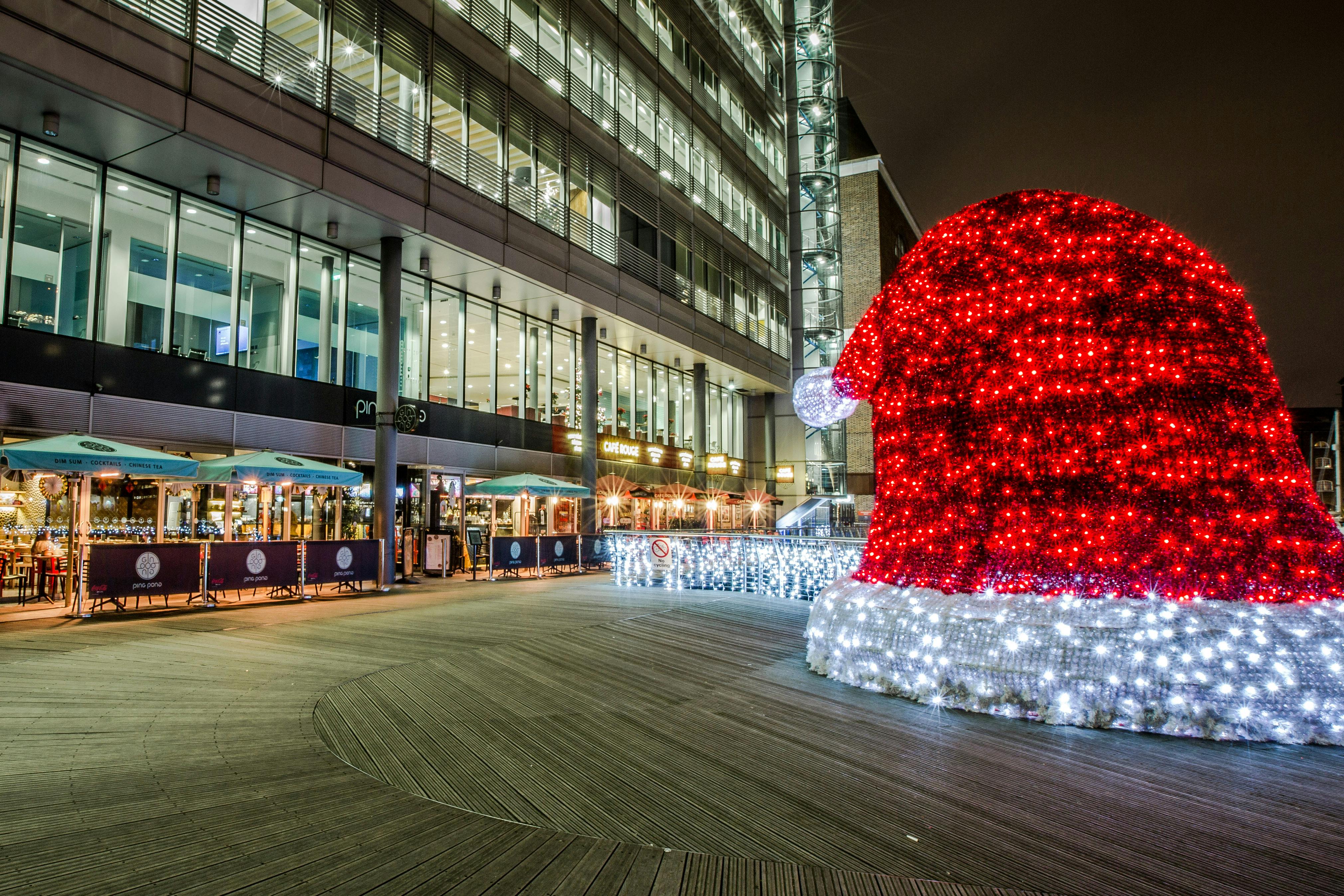 Christmas party at St Katherine Dock with festive lights and a large Santa hat.