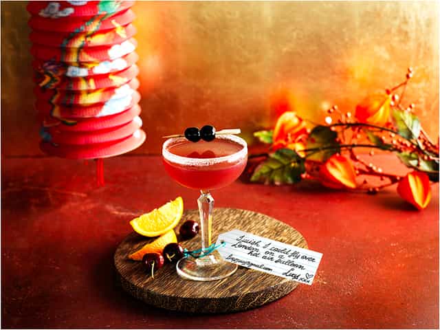 Cocktail on wooden board at Chinese New Year party, vibrant decor for themed events.