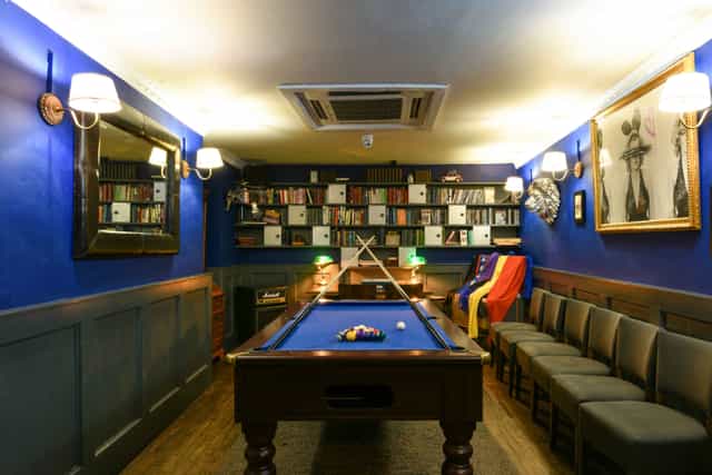 Stylish networking space with blue walls and pool table for casual meetings.