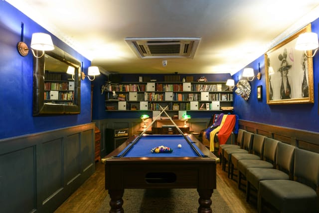 Stylish networking space with blue walls and pool table for casual meetings.