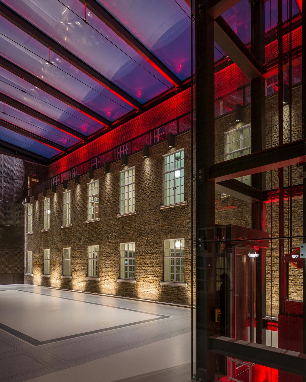 Modern event space at Hackney Town Hall with illuminated brick walls and glass roof.