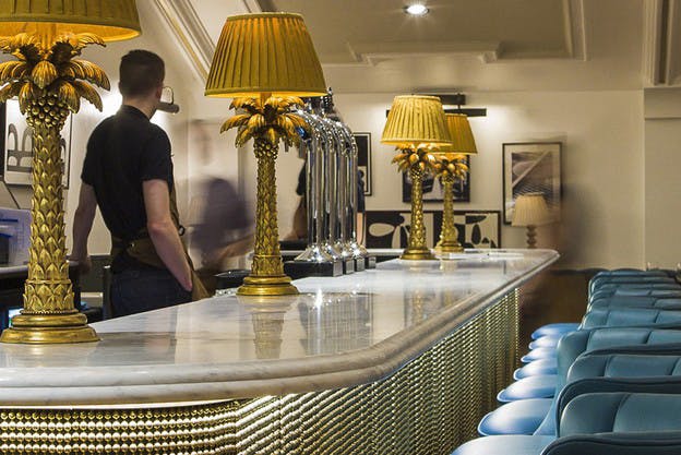 Stylish bar with marble countertop and golden lamps, perfect for cocktail receptions.