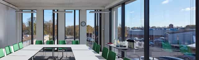 Modern meeting room with large windows, green chairs for productive brainstorming sessions.