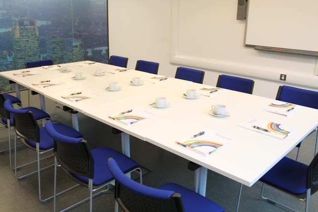 Community Hall meeting room with white table, blue chairs for professional gatherings.