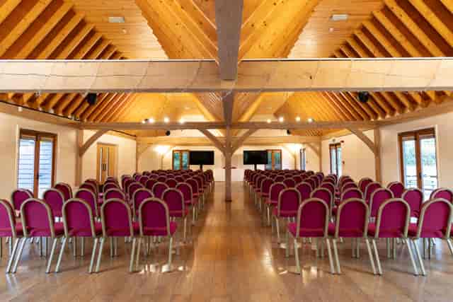 Cobbold Barn at Knebworth House, spacious venue with burgundy chairs for conferences.