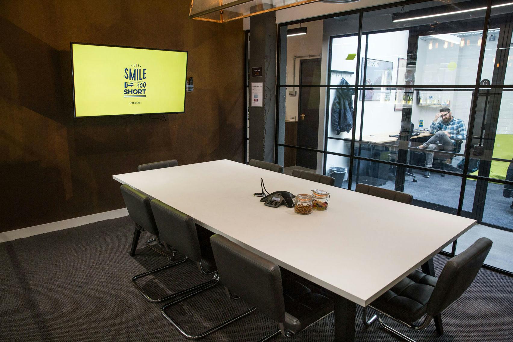 Modern meeting room at The Cube, featuring a large white table for collaborative sessions.