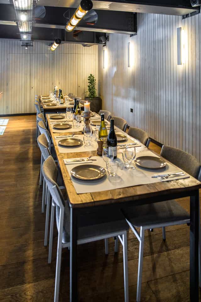 Mezzanine at Caravan City: Rustic wooden tables for high-end corporate dinners and private events.