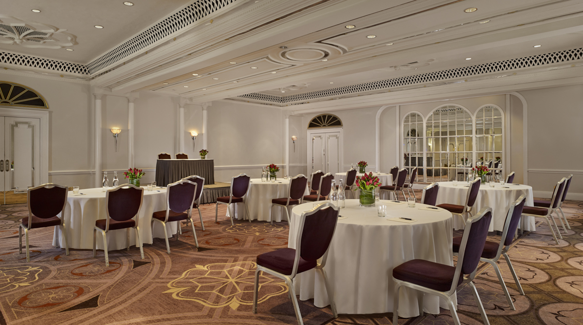 Elegant event space at The Tudor Rose, featuring round tables and floral centerpieces.