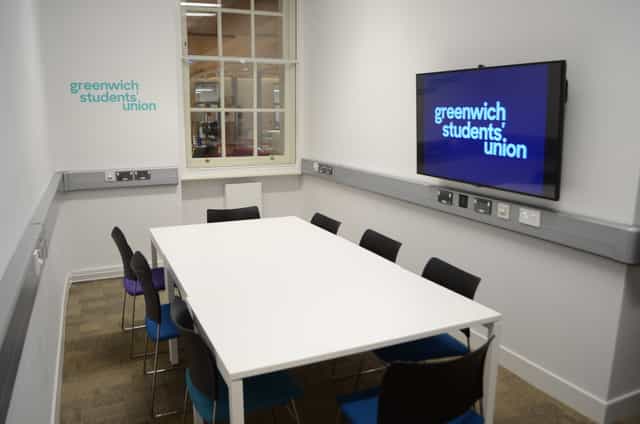 Modern small meeting room with colorful chairs, ideal for workshops and presentations.
