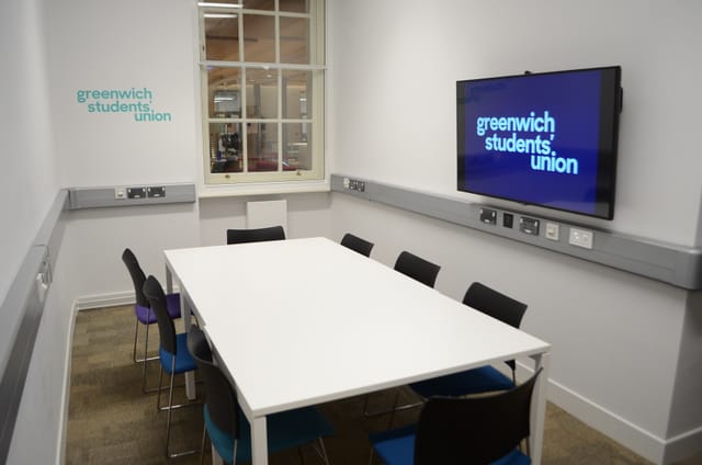 Modern small meeting room with colorful chairs, ideal for workshops and presentations.