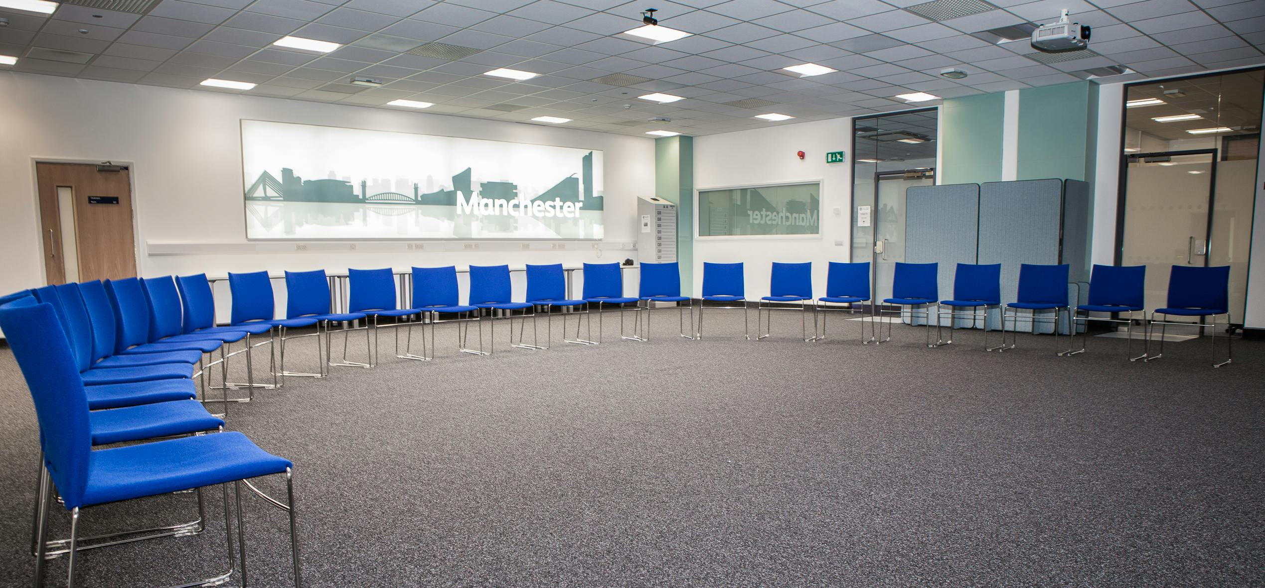 Versatile Manchester Room with blue chairs, perfect for workshops and meetings.