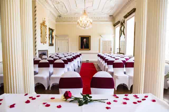 Elegant meeting room with white chairs and burgundy sashes, perfect for weddings and events.