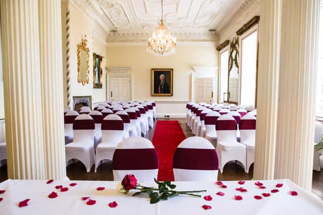 Elegant meeting room with white chairs and burgundy sashes, perfect for weddings and events.